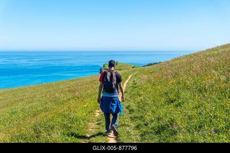 A hiker walking along a coastal path near the Zumaia flysch, Gipuzkoa. Basque Country-stock-foto