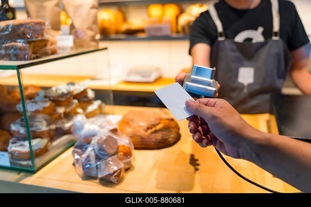Customer in the bakery shop buying an artisan bread from the baker in the workshop, paying with the card-stock-foto