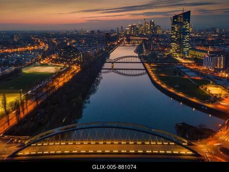 The lights of the European Central Bank (ECB) and the Frankfurt banking skyline glow in the evening. (Aerial view with a drone), Osthafen, Frankfurt am Main, Hesse, Germany-stock-foto