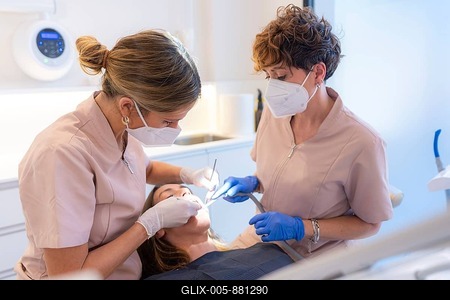 Dentist and assistant performing a filling on a tooth for a client in the modern dental clinic-stock-foto