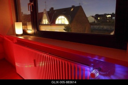 Radiator at a window with an illuminated thermostat, heating costs-stock-foto