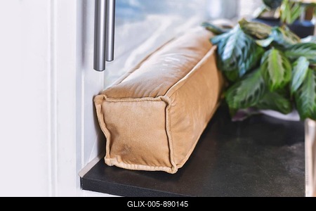 Draft excluder lying on window still to keep out cold air and save energy for heating in room-stock-foto