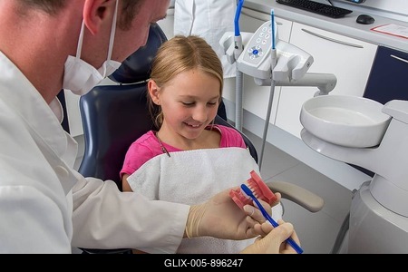 Dentist showing a girl the proper use of a toothbrush, Germany-stock-foto
