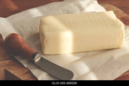Butter briquette, on wrapping paper, wooden chopping board and butter knife, breakfast, rustic style, no people-stock-foto