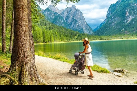 Tourist walking with stroller along lake in breathtaking mountain scenery of dolomites, italy, enjoying summer holiday-stock-foto