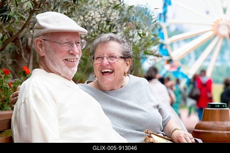 Laughing senior adult couple enjoying the carnival from the outdoor bench-stock-foto