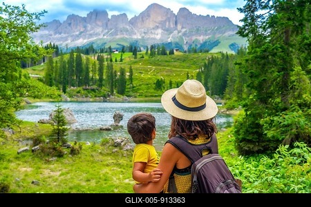 Mother carrying her son while enjoying breathtaking views of emerald waters at lake carezza, surrounded by the dolomites-stock-foto