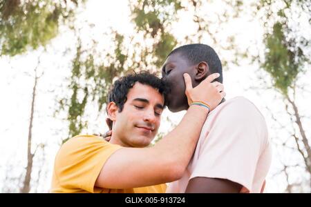 Lgbt concept, couple of multiethnic men in a park kissing each other on the forehead, romantic pose-stock-foto