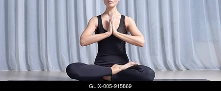 Young woman sits in a lotus position in a bright studio on a black mat. Yoga concept. Women's spiritual practices. Fitness.-stock-foto