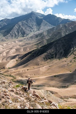Traditional Kyrgyz eagle hunter hunting in the mountains in a dry landscape, near Kysyl-Suu, Issyk Kul, Kyrgyzstan-stock-foto