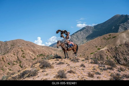 Traditional Kyrgyz eagle hunter riding with eagle in the mountains, eagle spreading its wings, hunting on horseback, near Bokonbayevo, Issyk Kul region, Kyrgyzstan-stock-foto