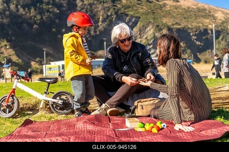 Grandmother, mother and child having fun during a picnic in a park, playing with toys and with a balance bike nearby-stock-foto