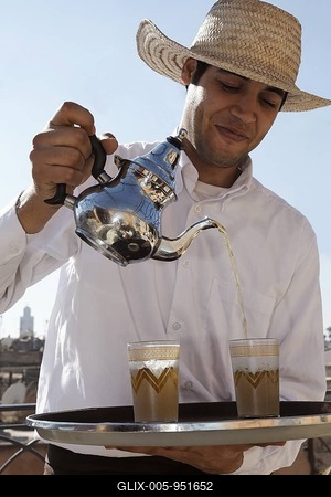 Waiter wearing straw hat pouring mint tea in the historic Medina quarter, Marrakesh, Morocco, Africa-stock-foto