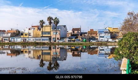 El palmar fishing village houses and palm trees mirrored in the calm albufera lake under a vivid blue sky, traditional waterfront architecture in valencia, spain-stock-foto