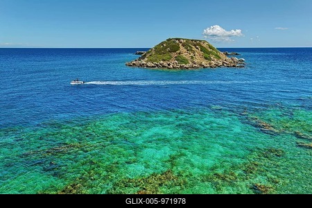 Small island Vrachonisida in front of the Grande Blue Beach in the turquoise blue sea with passing boat and blue sky with a cloud, Grande Blue Beach, Stegna, Rhodes Island, Greece-stock-foto