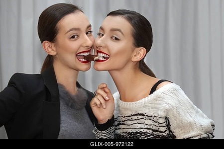 Two young girls eating one sweet from mouth to mouth-stock-foto