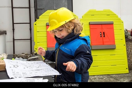 Little boy, 3 years, with toy hard hat, helping to build a playhouse, studying the blueprint-stock-foto