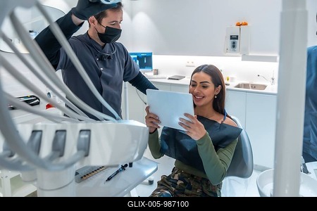 Dentist showing dental scan results on a tablet to smiling patient, in a modern dental clinic-stock-foto
