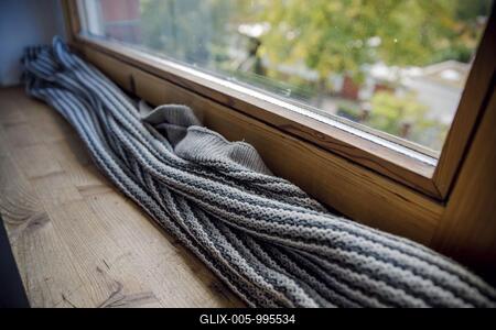 Symbolic photo on the subject of a cold flat. A blanket lies on the windowsill in front of a poorly insulated window to protect against cold air. Berl Berlin, Germany-stock-foto