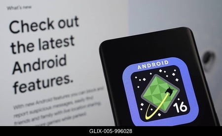 The logo of the Android 16 is displayed on a smartphone screen, with the android website visible on a computer screen in the background-stock-foto