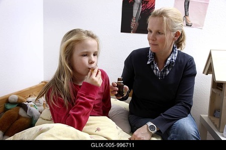 Girl, 10 years old, with a cold, flu, fever, cough, her mother is giving her cough syrup-stock-foto