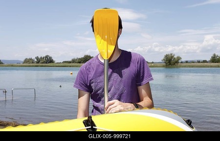 Young man holding paddle of rubber dinghy in front of his face, having fun boating, transition of Lake Constance into Seerhein river and Untersee lake, Taegerwilen, Switzerland, Europe-stock-foto