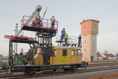 A hajdúszoboszlói vasútállomás átépítése során, az új felsővezetékekett teszik fel az erősáramű felsővezeték szerelők. A háttérben a lebontásra ítélt gőzmozdony töltő víztorony látható.-stock-foto