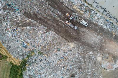 Garbage trucks unload garbage to a landfill, drone photo-stock-photo