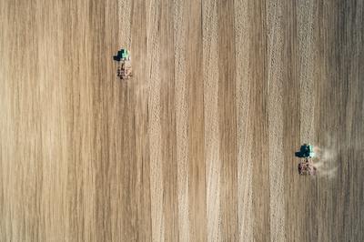 Aerial view of tractor plowing farm field in preparation for spring planting-stock-photo