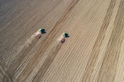 Aerial view of tractor plowing farm field in preparation for spring planting-stock-photo