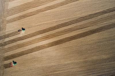 Aerial view of tractor plowing farm field in preparation for spring planting-stock-photo