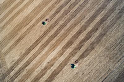 Aerial view of tractor plowing farm field in preparation for spring planting-stock-photo