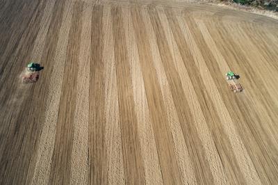 Aerial view of tractor plowing farm field in preparation for spring planting-stock-photo