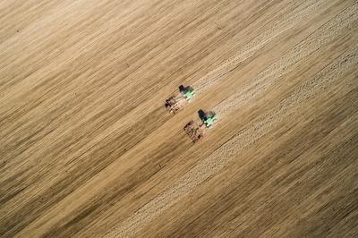 Aerial view of tractor plowing farm field in preparation for spring planting-stock-photo