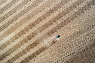 Aerial view of tractor plowing farm field in preparation for spring planting-stock-photo