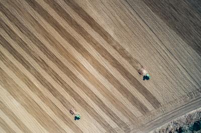 Aerial view of tractor plowing farm field in preparation for spring planting-stock-photo