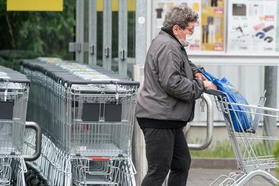 PECS - MAY 27 : Old woman go to shopping on the street  on 27 May 2020 in Pecs, Hungary. During coronavirus pandemic, everybody have to waering face mask-stock-photo