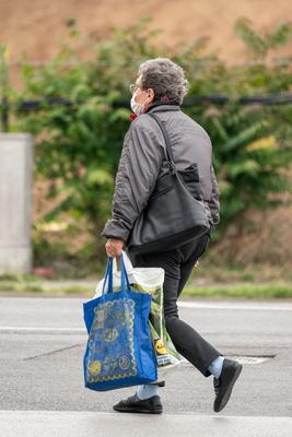 PECS - MAY 27 : Old woman go to shopping on the street  on 27 May 2020 in Pecs, Hungary. During coronavirus pandemic, everybody have to waering face mask-stock-photo