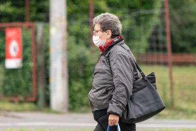 PECS - MAY 27 : Old woman go to shopping on the street  on 27 May 2020 in Pecs, Hungary. During coronavirus pandemic, everybody have to waering face mask-stock-photo