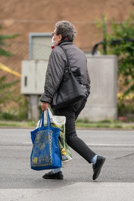 PECS - MAY 27 : Old woman go to shopping on the street  on 27 May 2020 in Pecs, Hungary. During coronavirus pandemic, everybody have to waering face mask-stock-photo