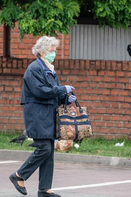 PECS - MAY 27 : Old woman go to shopping on the street  on 27 May 2020 in Pecs, Hungary. During coronavirus pandemic, everybody have to waering face mask-stock-photo