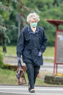 PECS - MAY 27 : Old woman go to shopping on the street  on 27 May 2020 in Pecs, Hungary. During coronavirus pandemic, everybody have to waering face mask-stock-photo