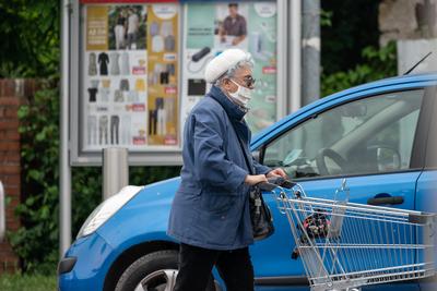 PECS - MAY 27 : Old woman go to shopping on the street  on 27 May 2020 in Pecs, Hungary. During coronavirus pandemic, everybody have to waering face mask-stock-photo