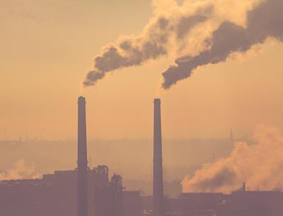 Smoking factory chimneys in morning backlit by rising sun-stock-foto