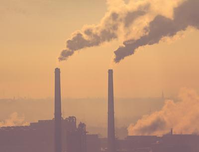 Smoking factory chimneys in morning backlit by rising sun-stock-photo