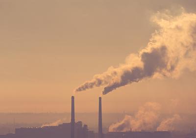 Smoking factory chimneys in morning backlit by rising sun-stock-foto