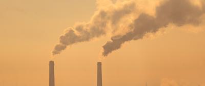 Smoking factory chimneys in morning backlit by rising sun-stock-foto