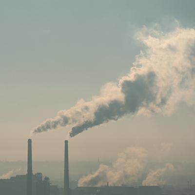 Smoking factory chimneys in morning backlit by rising sun-stock-foto