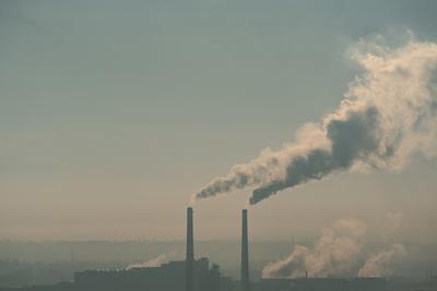 Smoking factory chimneys in morning backlit by rising sun-stock-foto