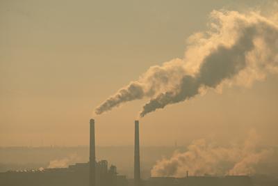 Smoking factory chimneys in morning backlit by rising sun-stock-photo